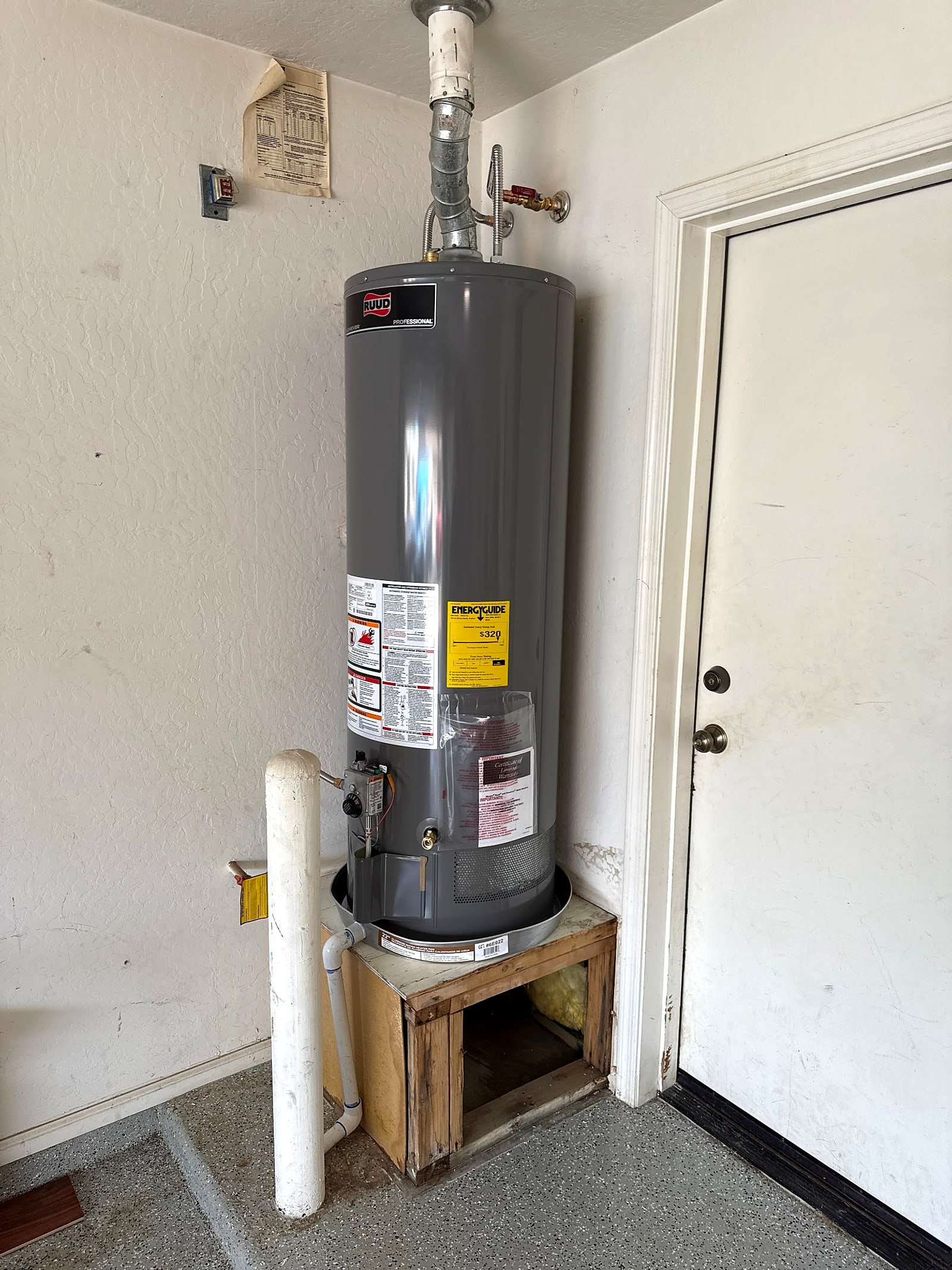 New gas water heater installed on a stand in a garage