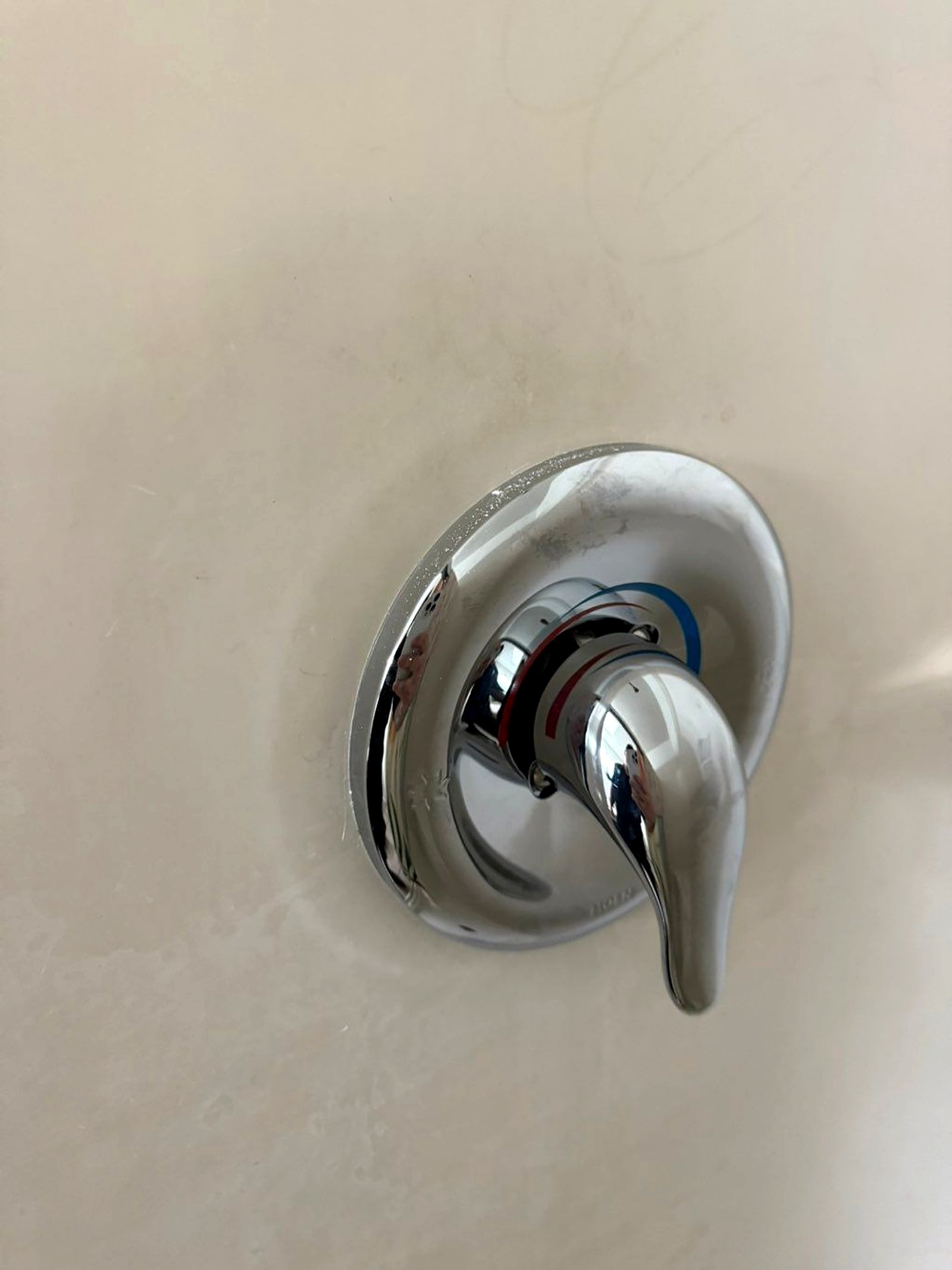 New chrome shower trim and valve handle on a white tub surround