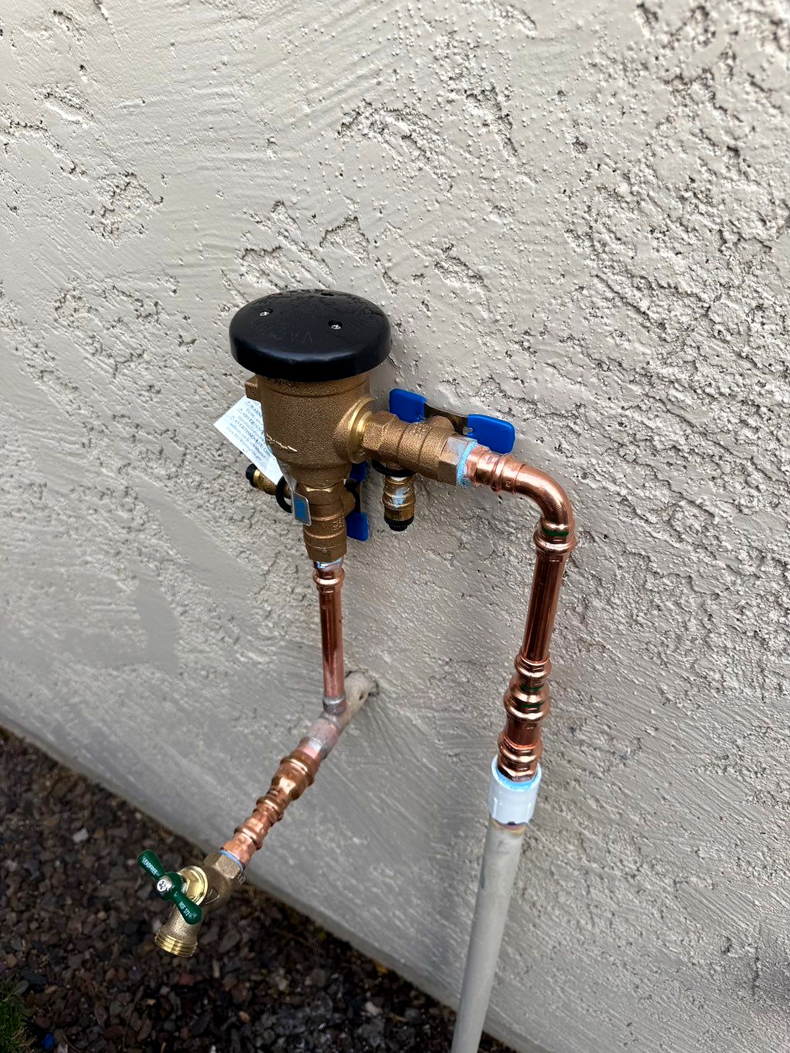 Brass valve and regulator on a stucco wall