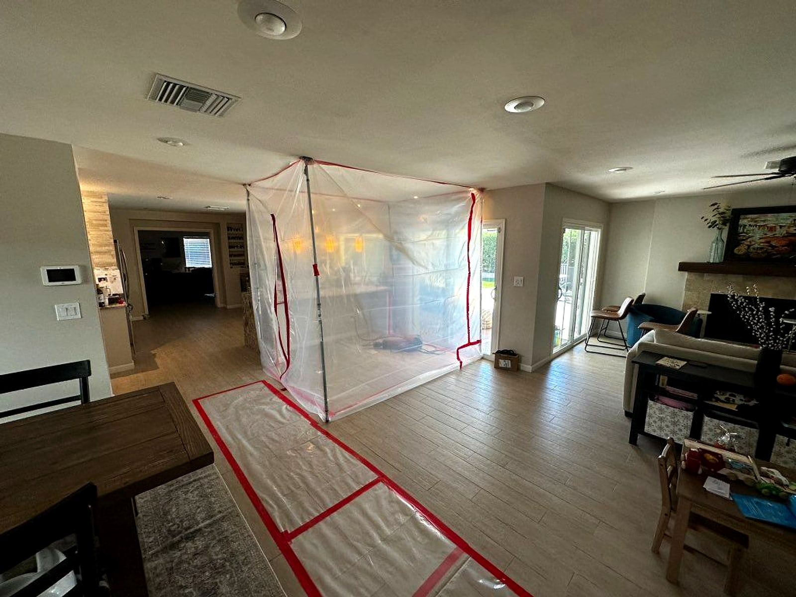 Living room sealed off with plastic sheeting and a floor runner while a repipe is under way