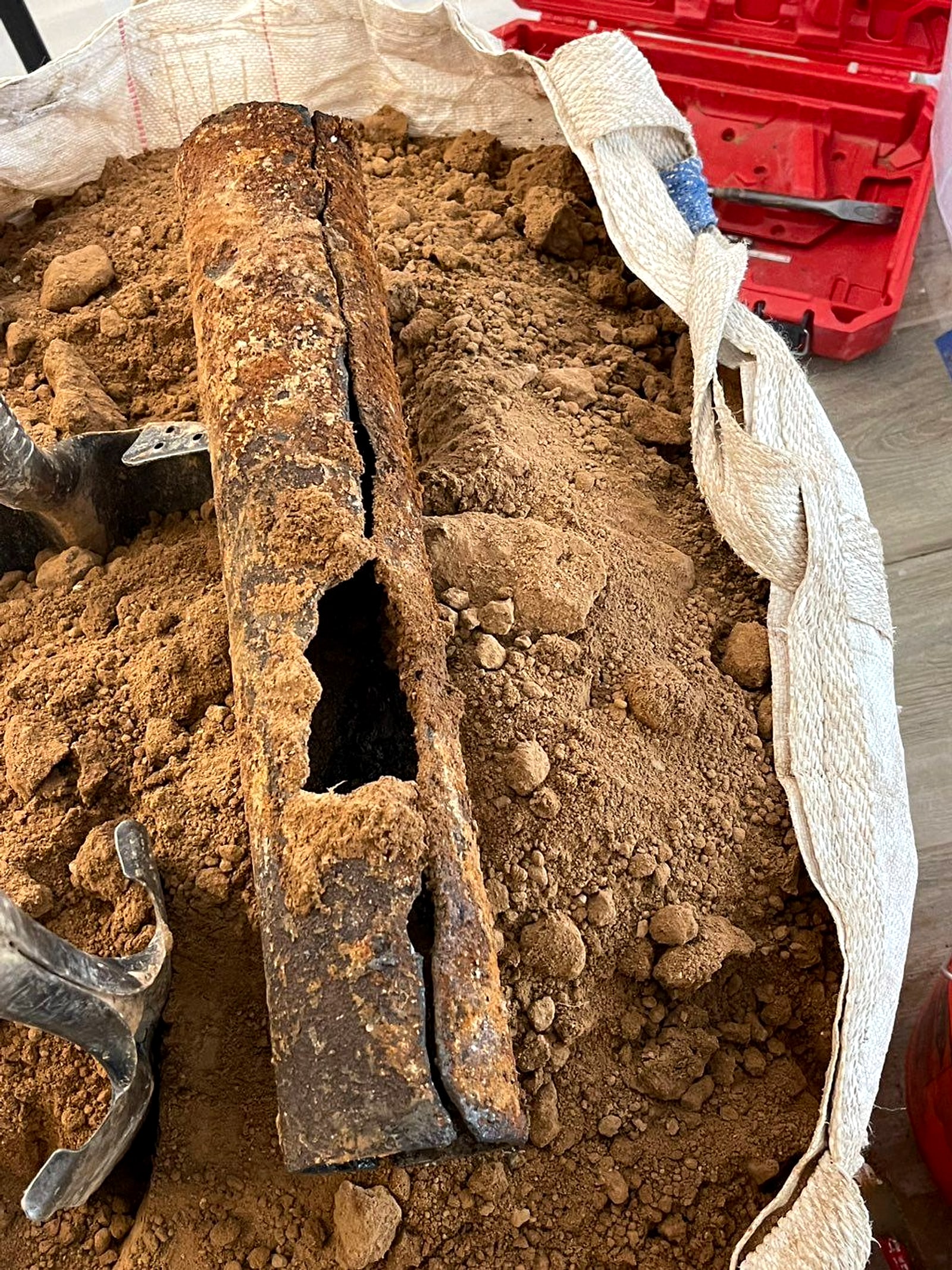 Cracked and collapsed section of old cast iron sewer pipe in a trench