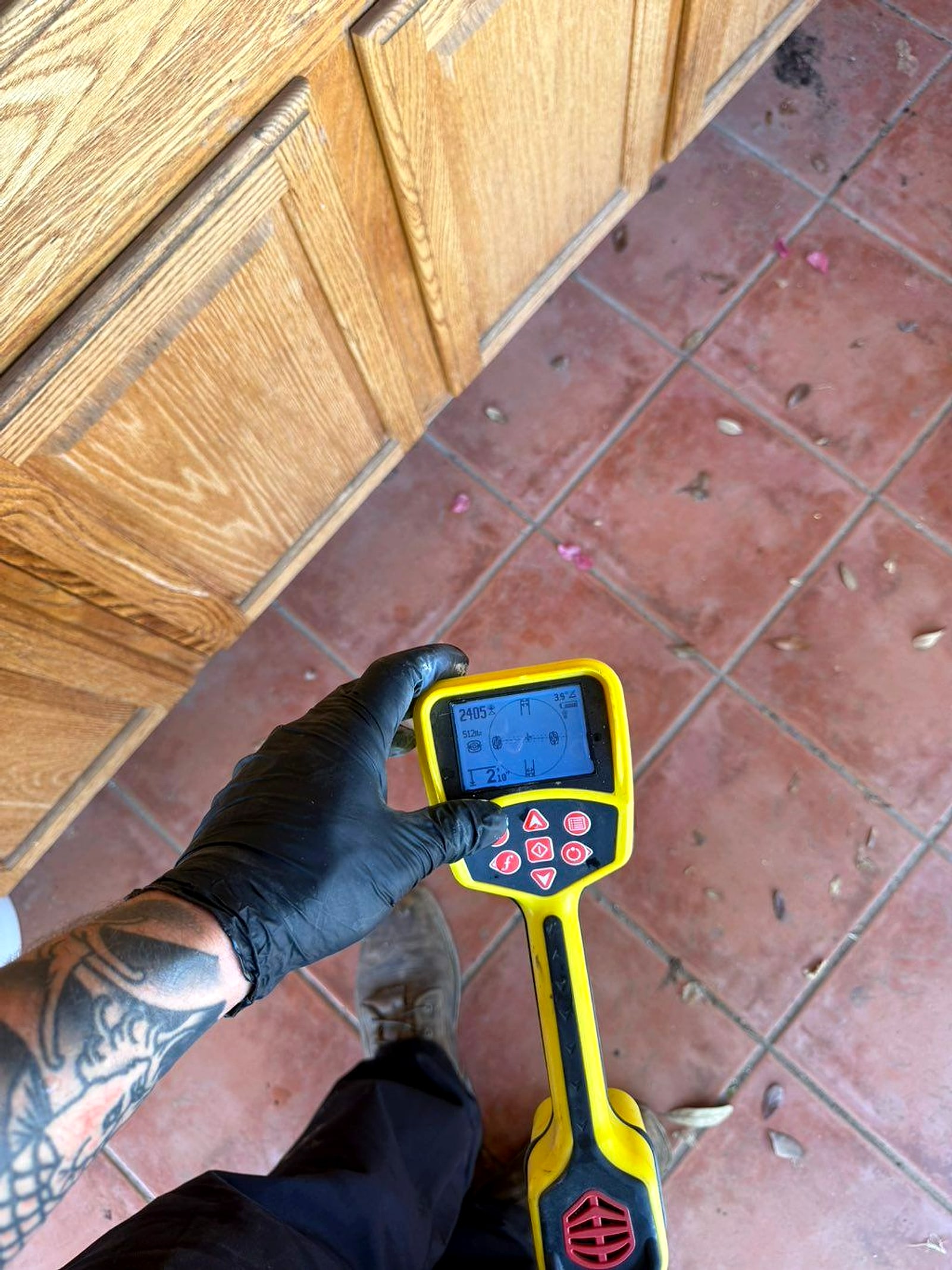 Leak detection meter held over a tile floor